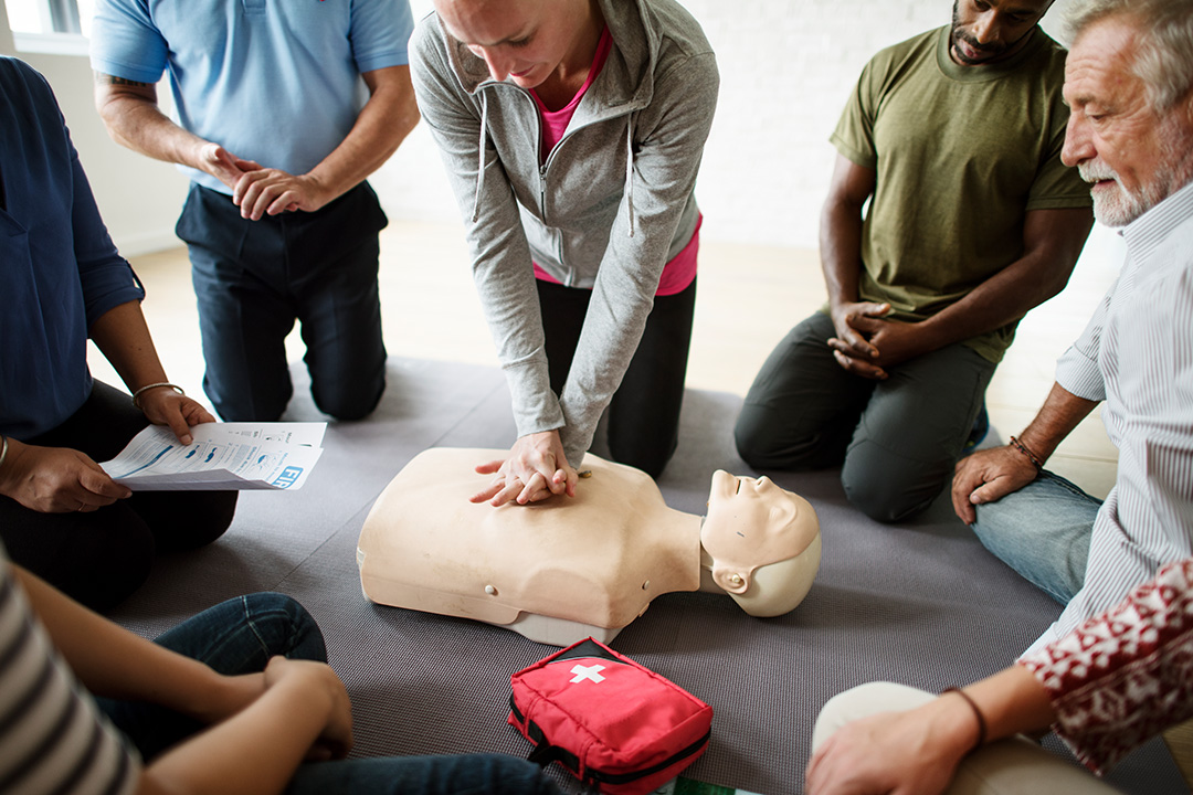 Woman delivering first aid class demonstrating CPR on manikin body